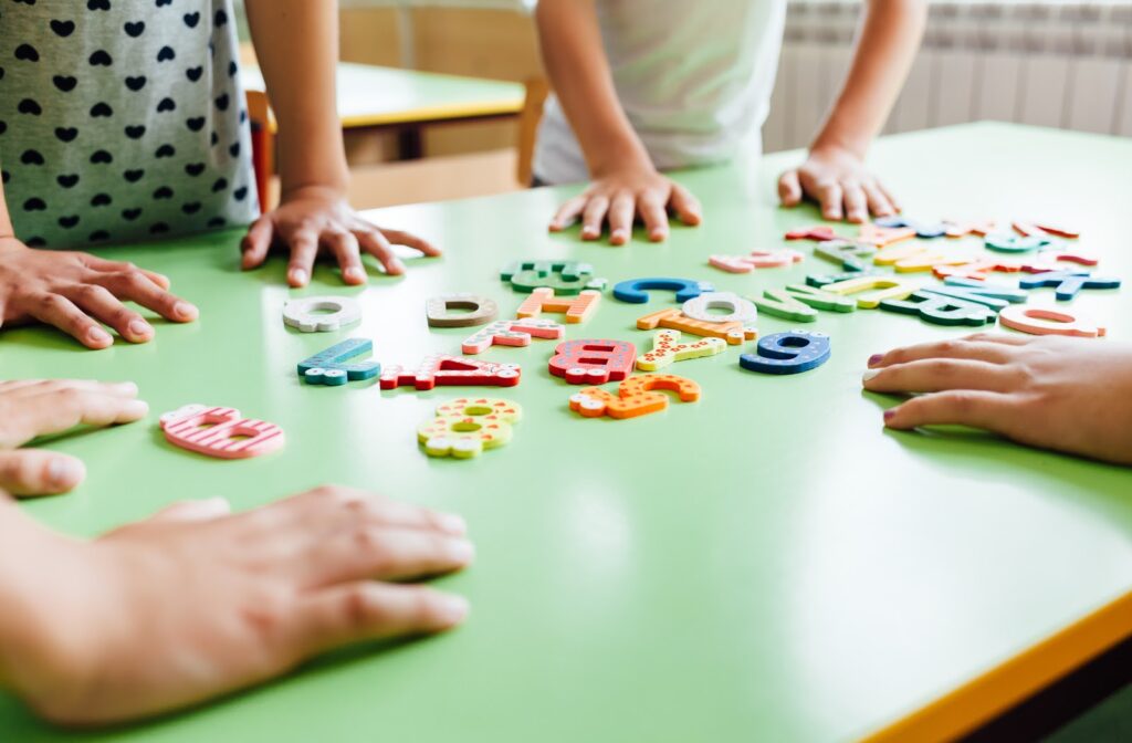 Children using social skills to share alphabet blocks.