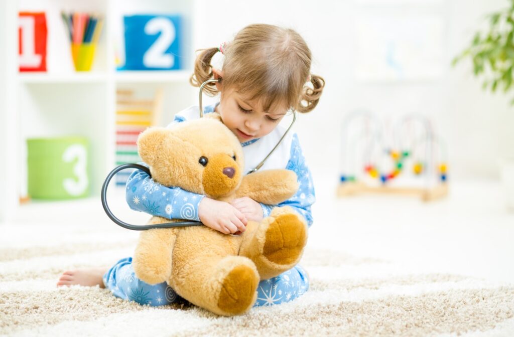 Young girl playing doctor with a teddy bear.