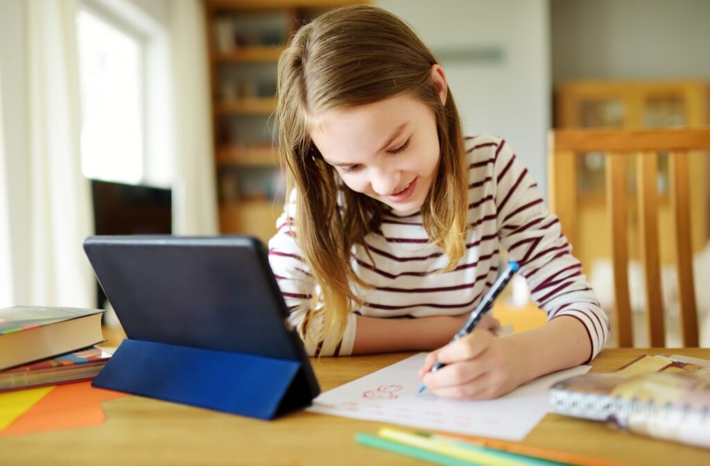 An older child working on her homework with the help of a tablet