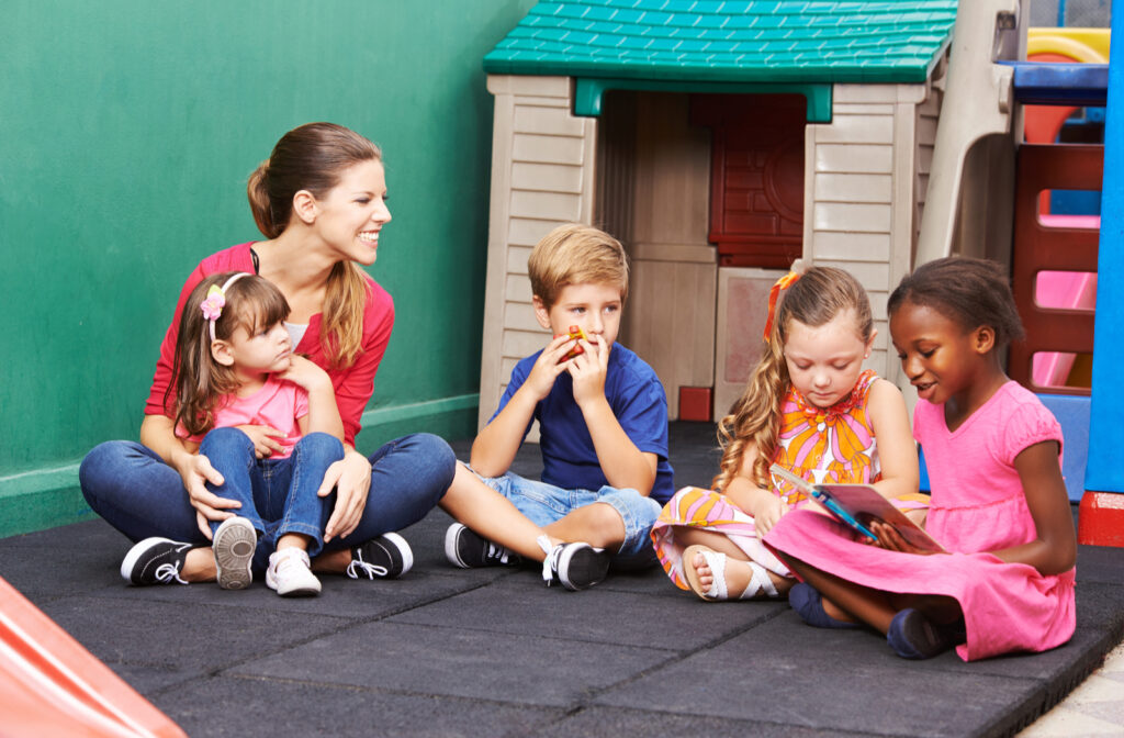 A group of four preschool kids sitting outside reading out loud to each other