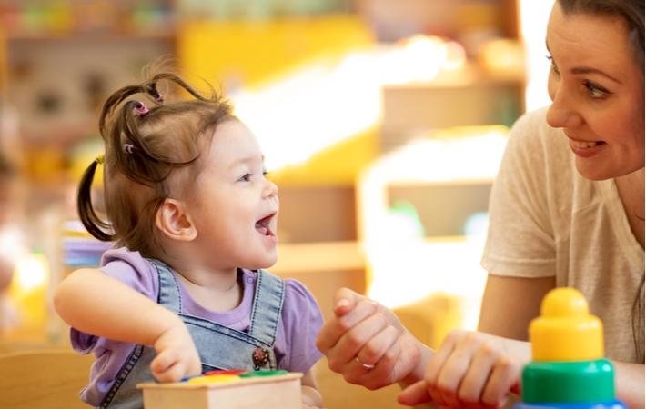 A Montessori teacher communicating with a little girl while she's doing activities