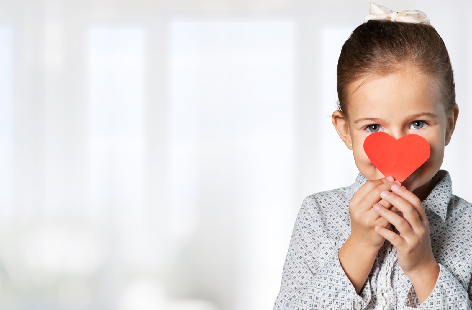 A little girl holding up a heart cut out symbolizing respectfulness and discipline