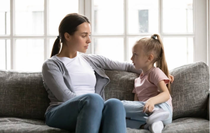 A mother sitting on a couch and listening to her daughter's thoughts and opinions