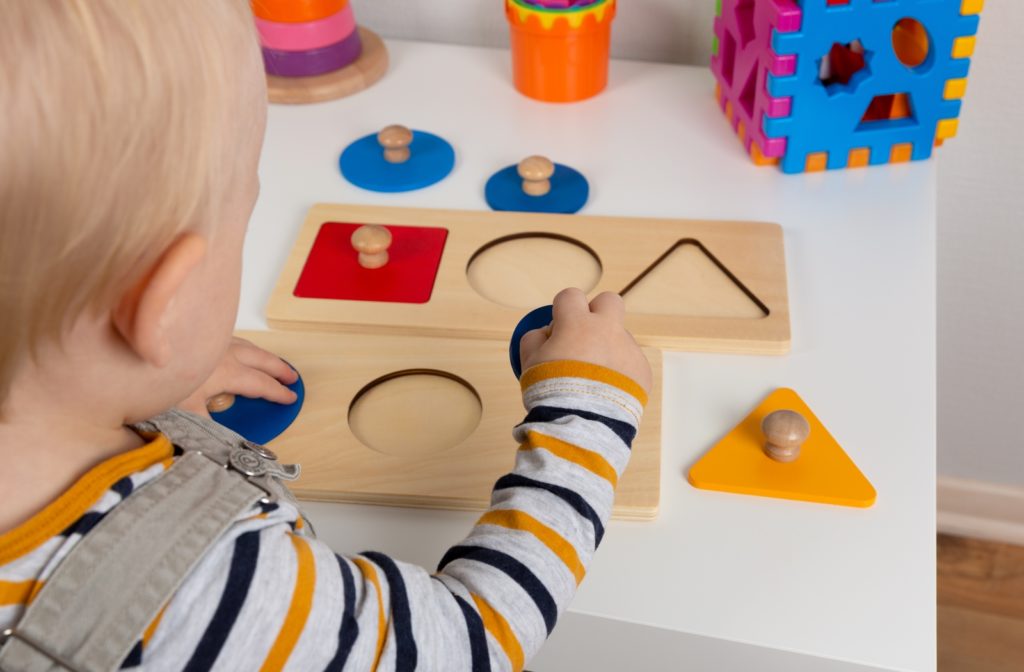 A child playing with geometric shapes to practice shape recognition and fine motor skills.