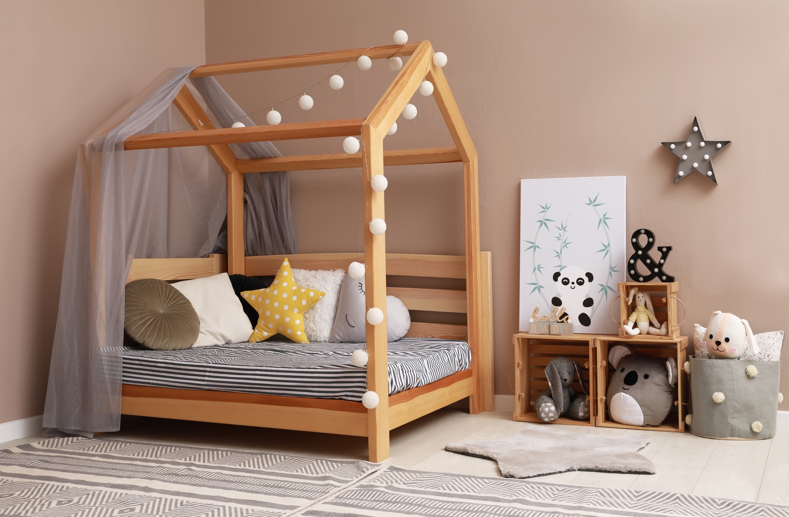 A Montessori floor bed built out of wood with lights strung along the frame.