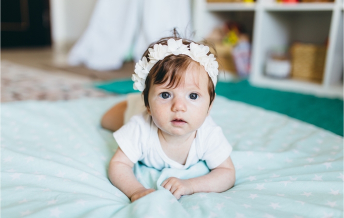 A little girl lying on her stomach on a floor bed.