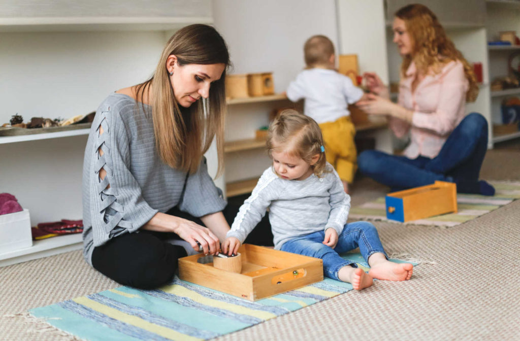 A mother and daughter participating in a Montessori group lesson, focused and engaged in their work.