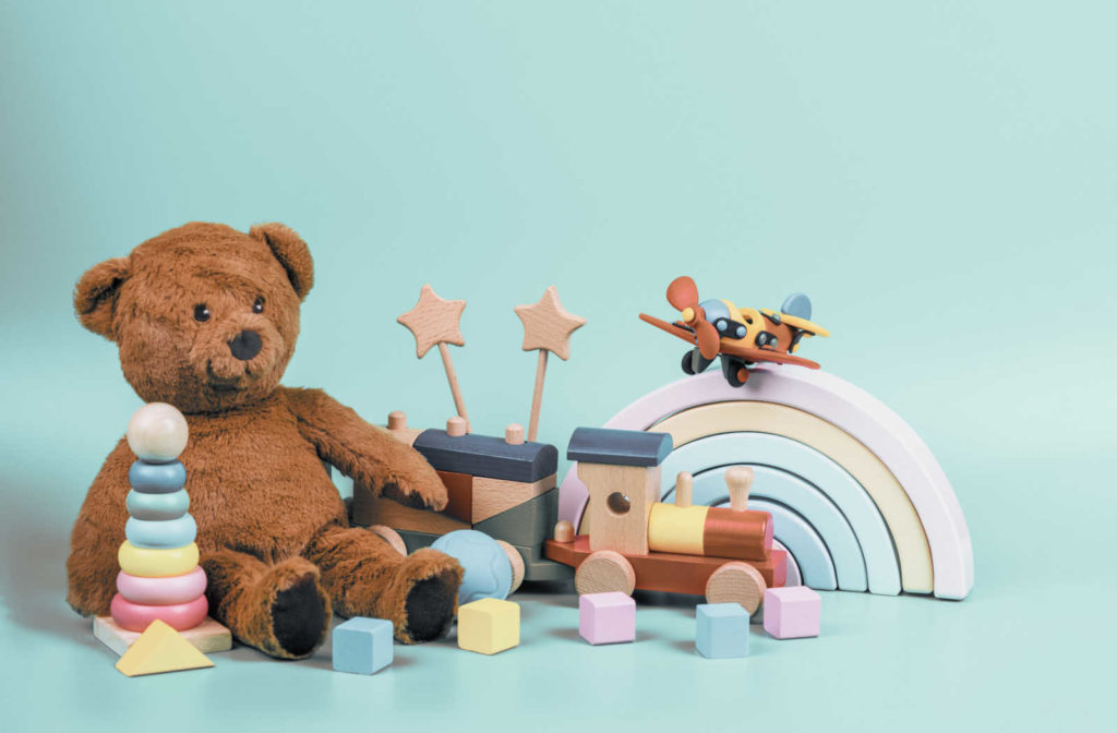 A collection of children's toys including a teddy bear and wooden blocks on a colorful rug.