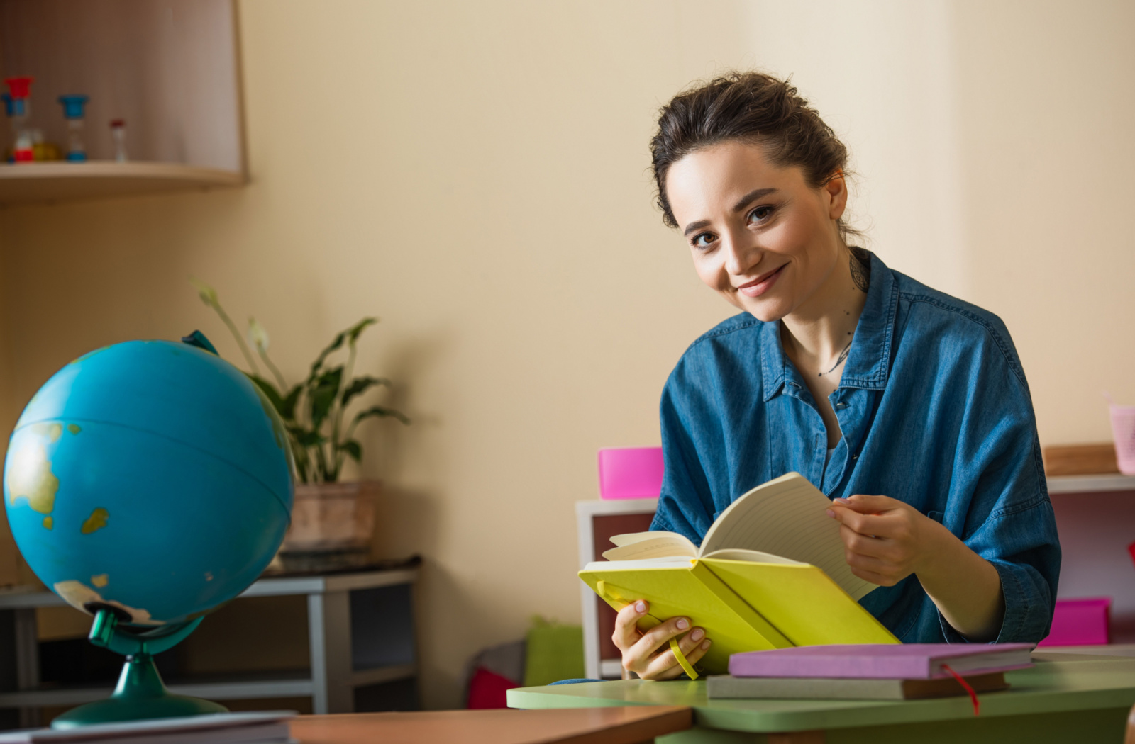 A female Montessori teacher smiling and holding a book