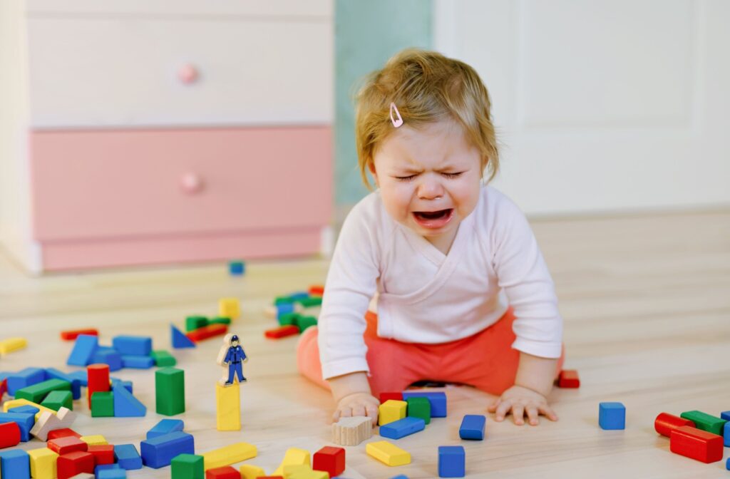 A baby girl crying because of her frustration on her toy blocks.