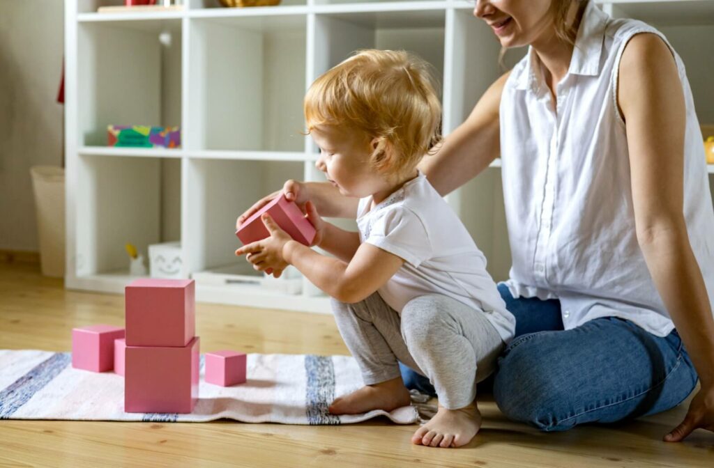 Young parent and their little baby assemble a pink Montessori tower to support early development at home.