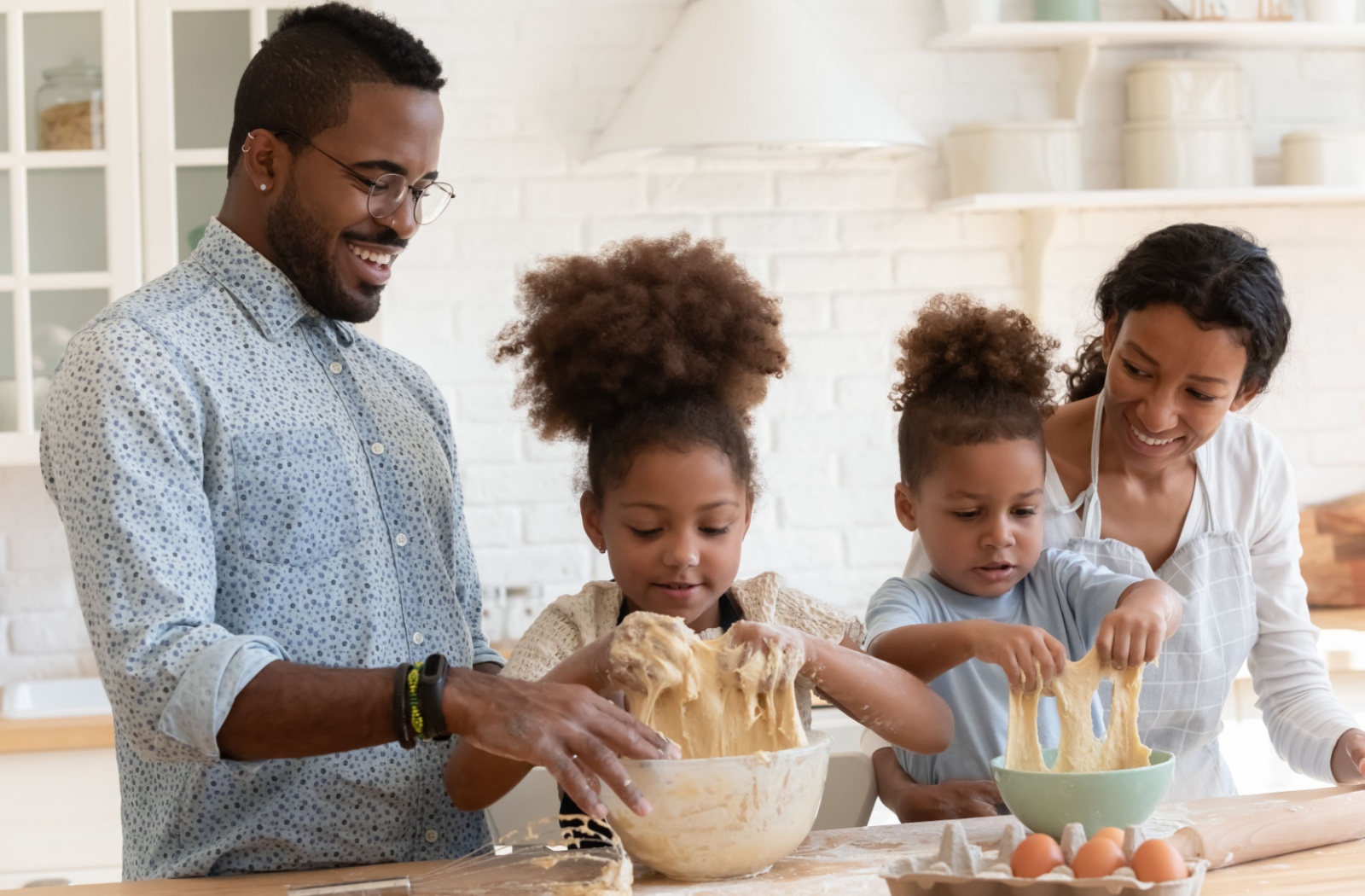 Parents baking with their children to indroduce sensory play, an activity encouraged by the Montessori method.