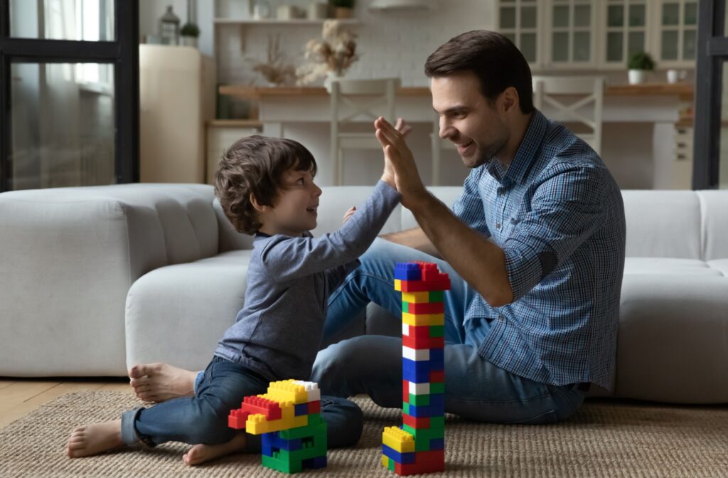 A parent high-fives their child after working together to build a tower, encouraging collaboration and fine motor skills.