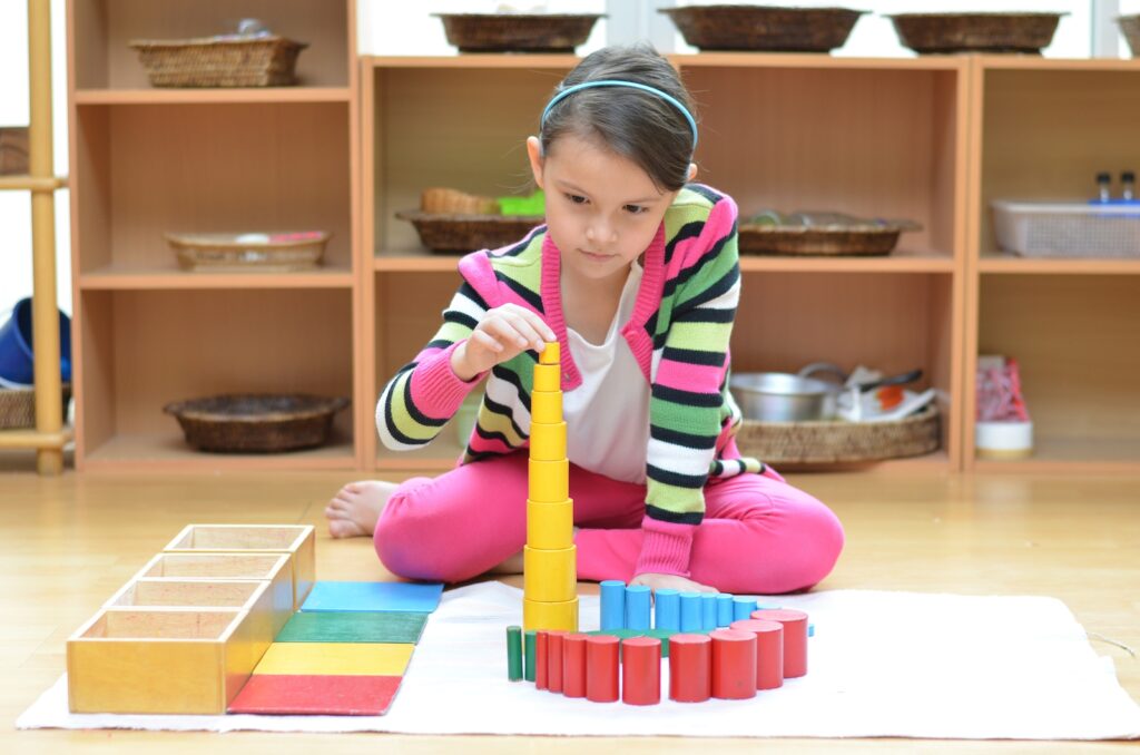 School aged girl building tower with Montessori blocks.